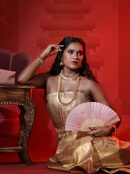 A full portrait from our dusky beauty concept shoot. The golden outfit and makeup make her skin look rich and luminous against the dramatic red background.