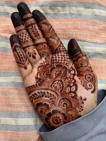 A rare design on my own right hand. This piece focuses on a dense cluster of floral and paisley patterns on the palm, with detailed work on the fingers.