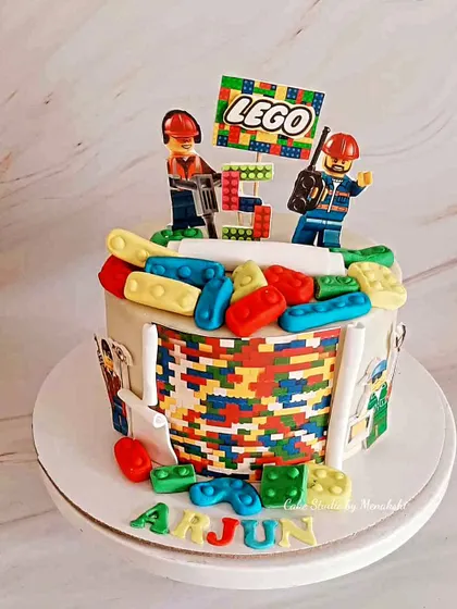 A colourful Lego themed cake for a 5th birthday. The cake is decorated with edible Lego bricks and construction worker figures for a fun and creative design.
