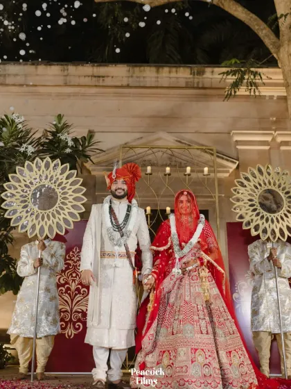 A regal portrait of the couple after their ceremony, standing together in their magnificent wedding outfits.