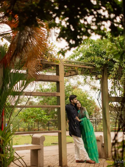 A quiet moment of togetherness in a lush green park, leaning against a rustic wooden archway.