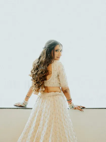 A beautiful portrait of the bride from behind, showcasing her elegant hairstyle and the delicate details of her lehenga. It's a graceful and timeless shot.