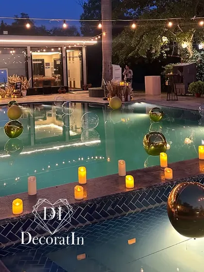 A different angle of the decorated pool, capturing the beautiful reflections of the string lights and candles on the water at dusk.