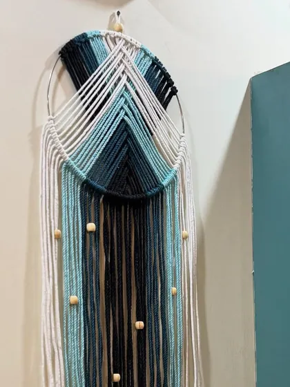 One of the ombre dreamcatchers hanging on a wall. It's a perfect piece of decor for a bedroom or a calming space.
