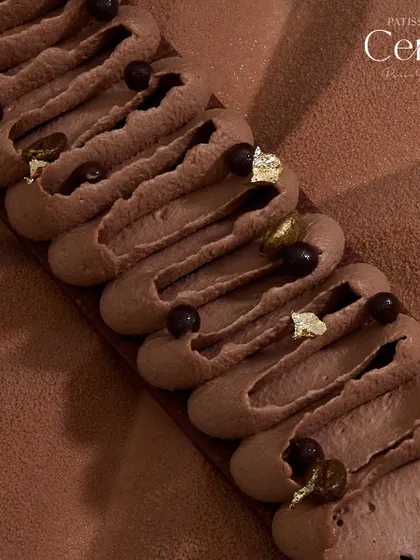 A close-up of the piped detail on the Mochaccino, adorned with chocolate pearls and gold leaf.