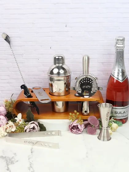 Elevate your home bar with this luxe bar set. It includes a cocktail shaker, strainer, jigger, and other essential tools, all neatly organized on a wooden stand. It's a perfect gift for any cocktail enthusiast.