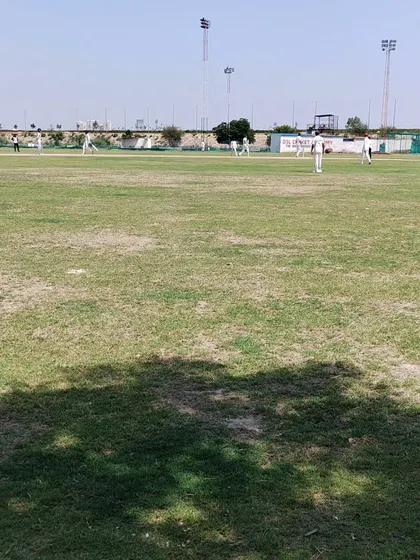A wide view of our lush, full-sized cricket ground during a match. We ensure our players get ample time in the open field for fielding drills and competitive games, which is essential for developing a complete cricketer.