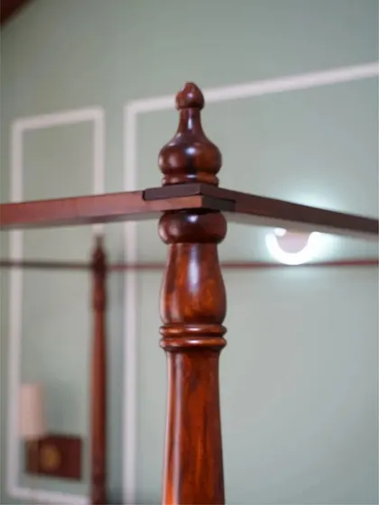 A detail shot of the four-poster bed's corner, highlighting the precisely turned finial and the quality of the joinery.