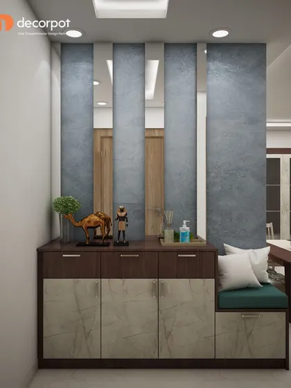 A foyer design that plays with texture and reflection. It features a two-tone cabinet with a seating nook, set against a textured blue wall with vertical mirror panels that enhance the sense of space.