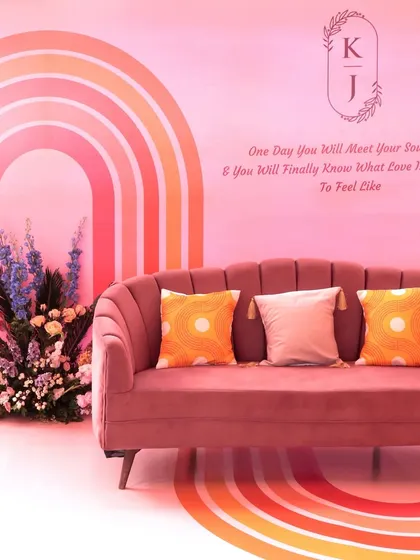 A chic seating nook with a pink rainbow backdrop and a personalized quote, creating another beautiful photo spot for the couple and guests.