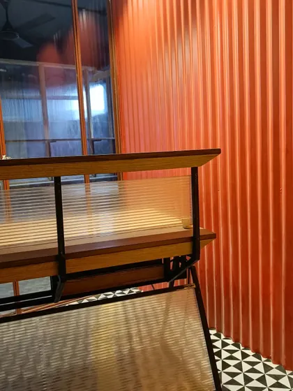 A close-up of a custom-designed desk with a fluted panel, set against a corrugated orange wall. This image highlights our focus on combining industrial materials with refined details to create unique and tactile office furniture.