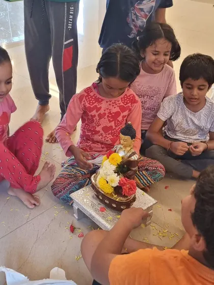 A close-up of the children's joyful offering of flowers to the Buddha statue. Their spontaneous reverence and happiness is a lesson for all of us.