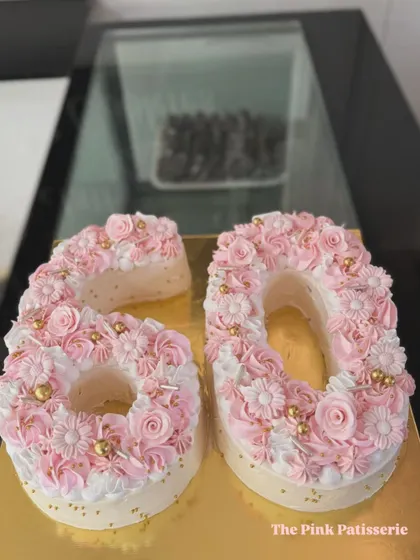 A close-up view of the dreamy pink "60" monogram cake, showcasing the detailed floral piping work that makes this design so special.
