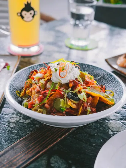 A generous bowl of loaded nachos, topped with salsa, sour cream, and jalapeños. Perfect for sharing.