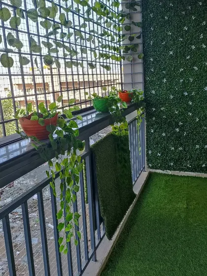 This balcony combines the best of both worlds. I installed an artificial grass floor and a green wall panel, and the client added their own touch with a mix of real and artificial potted plants along the railing.