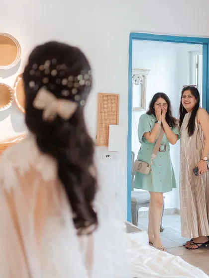 The priceless reaction of bridesmaids seeing the bride in her dress for the first time. This "first look" is a moment of pure, unscripted emotion and joy.
