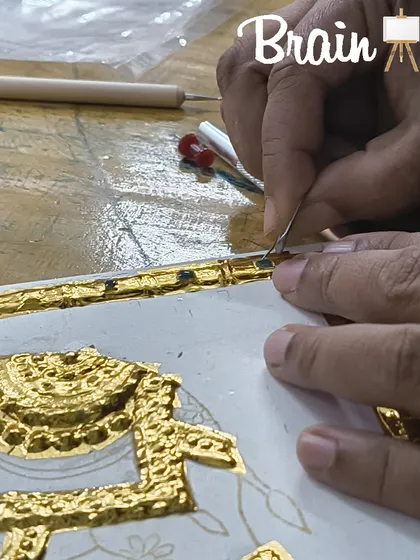 Another view of the meticulous process of setting stones and refining gold work in a Tanjore painting.