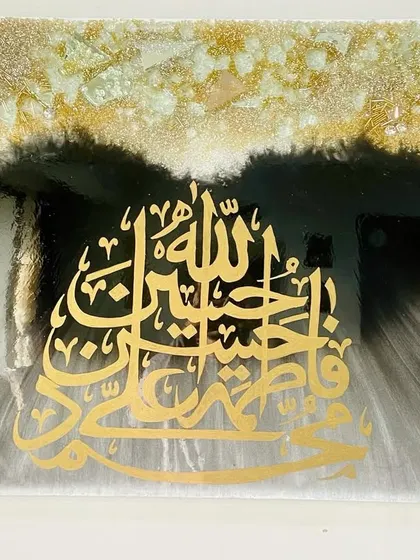 This piece features the sacred names of the Panjatan Pak. The golden calligraphy is set against a dramatic black and grey background with a burst of light effect, all under a glossy resin finish.