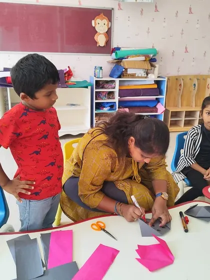 Teachers assist our youngest campers with a paper craft activity, fostering creativity and fine motor skills.