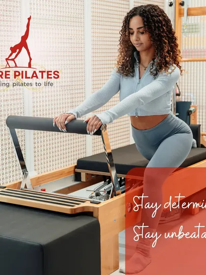Stay determined and unbeatable. A client holds a strong lunge position on the Reformer, demonstrating focus and control.