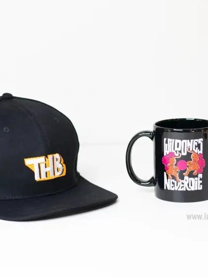 A custom black snapback cap with a bold, colorful embroidered logo for 'THB'. Paired with a custom mug, this shows how we can create matching sets of merchandise.