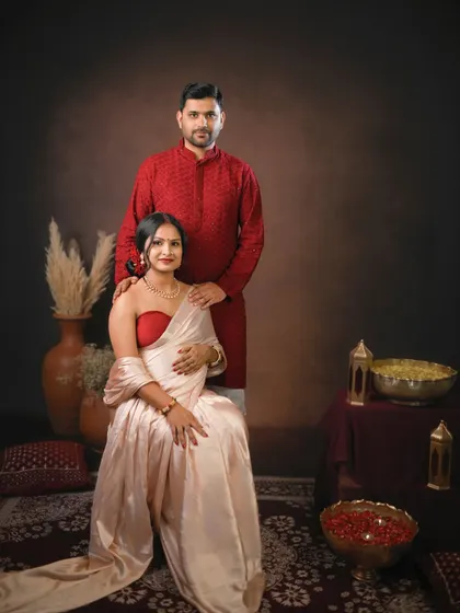 A formal and elegant portrait of the couple. Their coordinated red and cream outfits look stunning in this classic, traditionally styled studio shoot.