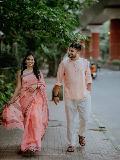 A full-length shot of the couple strolling down a sidewalk, their coordinated pastel outfits and happy expressions creating a light and airy pre-wedding portrait.