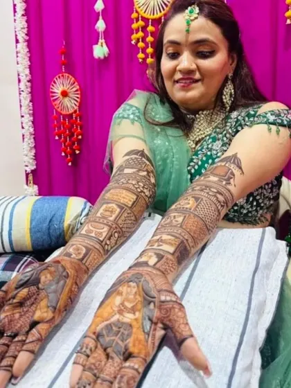 A happy bride showing her completed portrait mehndi, featuring detailed figures of herself and the groom.