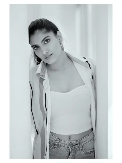 A casual portrait in black and white. The natural light from the window and the relaxed pose give this image an authentic, lifestyle feel while maintaining a classic aesthetic.