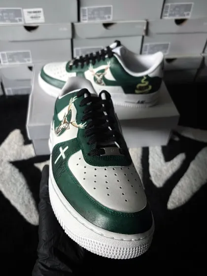 A front-facing shot of the Jägermeister-themed AF1s. This angle highlights the clean lines and detailed artwork on the front and side of the shoe, set against a background of fresh sneaker boxes.