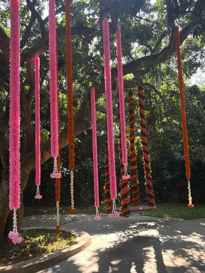 Pink and orange floral strings hang from a tree, creating a vibrant and festive atmosphere.