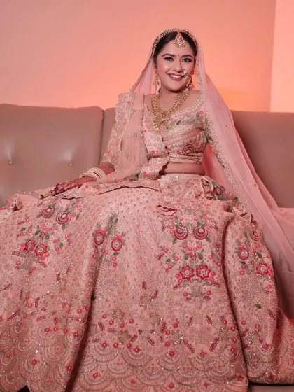 A full portrait of the bride in her pastel pink lehenga. The soft glam makeup completes this dreamy and elegant look.