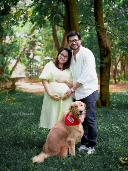 The perfect family portrait, with their furry friend right by their side. This outdoor shot shows the love that is expanding to welcome a new member.