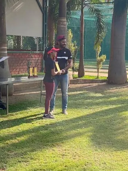 A young girl proudly accepts her award at the KSLTA tournament prize ceremony. These events are crucial for building competitive experience in a structured environment.