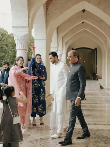 The groom, Moin, is greeted with a shower of flower petals as he arrives for his Nikah ceremony. It's a beautiful tradition captured in a candid moment.