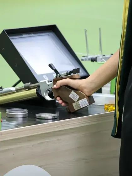 A close-up of a shooter's pistol and the electronic target system. We invest in the best equipment to ensure our athletes have every advantage in their training.