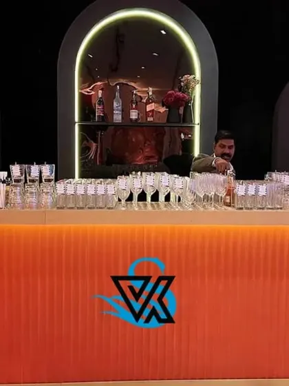 A head-on view of our modern, fluted orange bar. The clean lines, bold color, and arched back-shelving create a sophisticated focal point for a cocktail event.