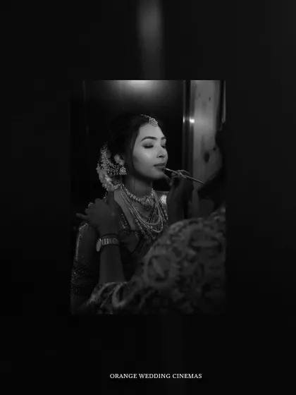 An artistic black and white shot of the bride getting her makeup done, seen as a reflection.
