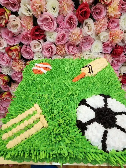 A large 3kg sports-themed cake combining both cricket and football. The "grass" is piped with buttercream for a realistic texture.