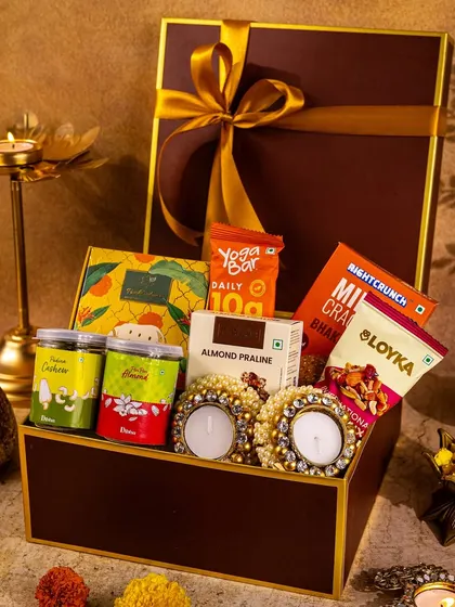 A premium Diwali hamper filled with snacks and candle diyas, shot in a warm, moody light to convey a sense of indulgence and festive warmth.