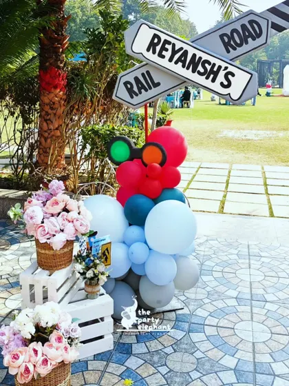 Another view of the custom railway crossing sign, this time showing the accompanying floral arrangements and props that helped blend the theme into the outdoor party space.