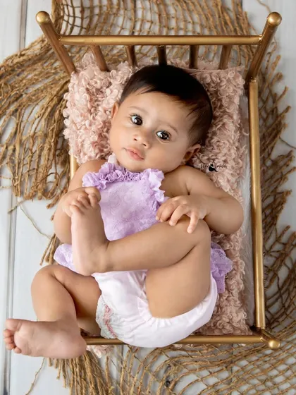 Six month old Adira lying on a miniature bed, looking up at the camera with her big, beautiful eyes.
