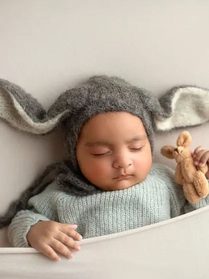 Even simple props can be so effective. Here, a cozy bunny hat adds a touch of whimsy to this portrait of a sleeping twin, showing how accessories can enhance a newborn photo.