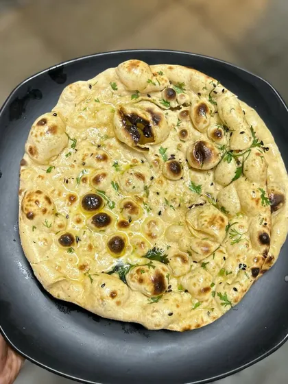 The perfect pairing: a hot, fluffy Butter Tandoori Roti. Made fresh in our tandoor, it's the ideal vessel for soaking up the delicious gravy of our Nihari or other curries.