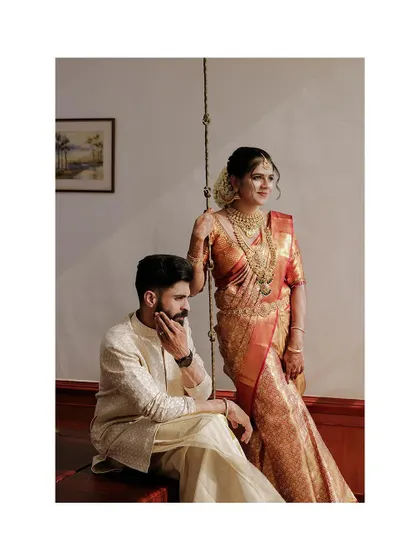 A regal portrait of a couple posing with a traditional indoor swing (oonjal).