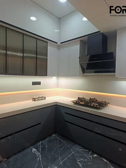 The corner of a U-shaped kitchen, showing how the handleless design and continuous countertop create a seamless flow. Fluted glass overhead cabinets add a touch of texture and elegance.