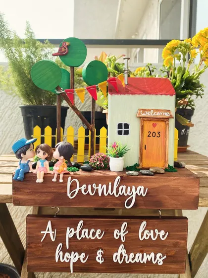 A home is a place of love, hope, and dreams. This two-tiered nameplate beautifully captures that sentiment, with a charming house scene on top and a heartfelt quote below.