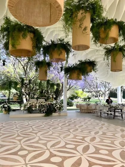 A dance floor with a custom-printed pattern, set under a tented ceiling with hanging greenery installations. The design ensures that even the functional elements of the event are beautiful.