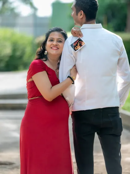A creative and sweet announcement photo. The mom-to-be peeks out from behind her partner, holding up their baby's ultrasound picture.