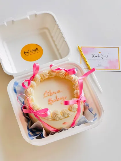 A cute "Libra Baby" bento cake. This mini cake features vintage-style piping and pink ribbons, all neatly packed in a personal-sized box.
